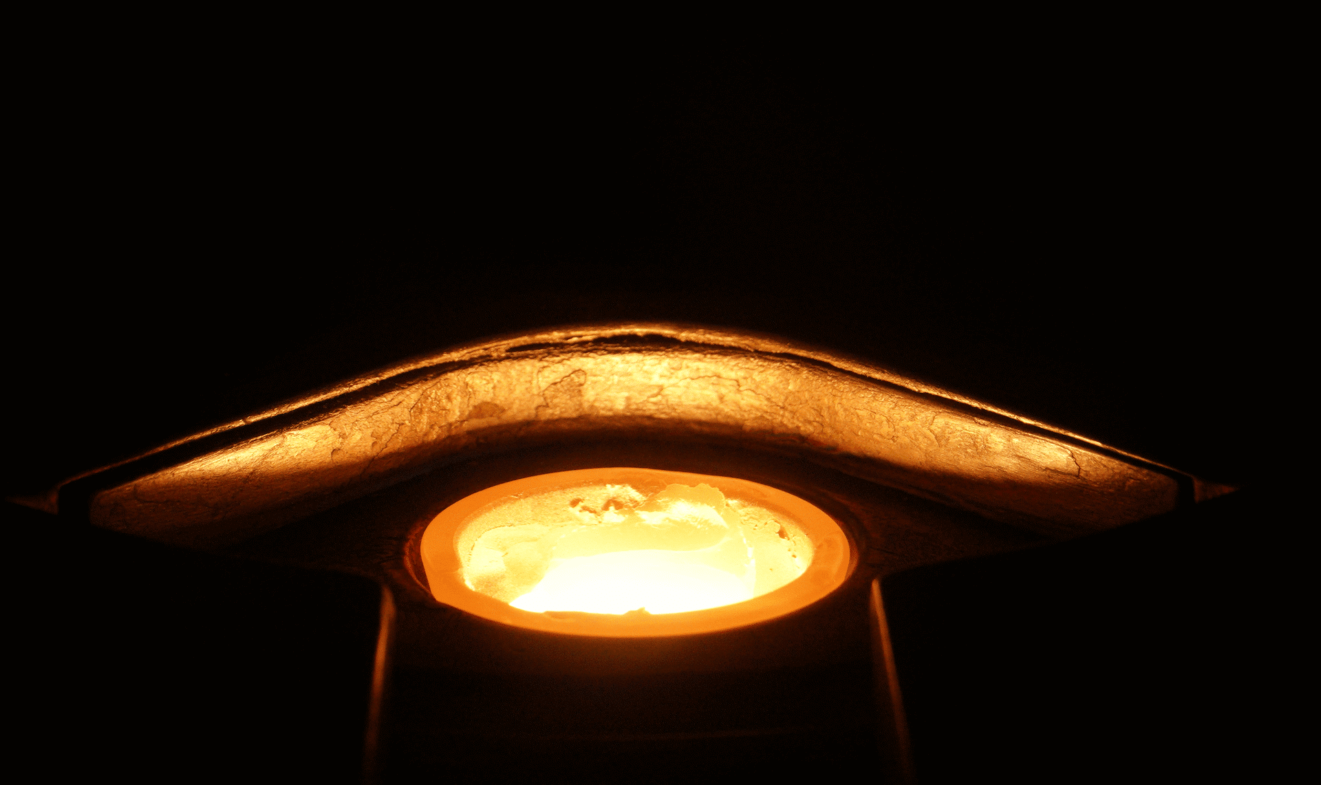 Close-up of a glowing orange light inside a circular fixture, surrounded by a dark background.