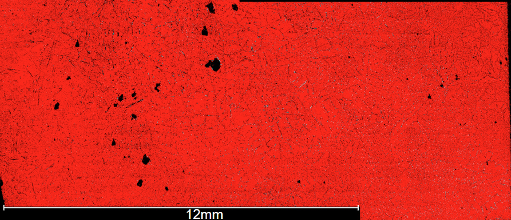 Microscopic FESEM view of a red surface with a network of thin black cracks, scattered dark spots, and a 12mm scale bar.